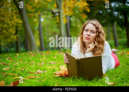 Giovane e bella donna plussize la lettura di un libro in autunno park Foto Stock