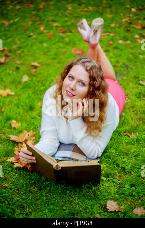 Giovane e bella donna plussize la lettura di un libro in autunno park Foto Stock