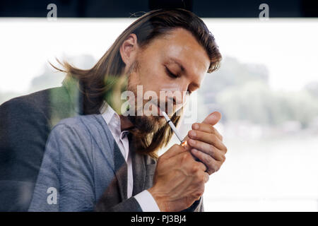 Vista laterale al giovane imprenditore godendo il suo sigaro in pausa Foto Stock