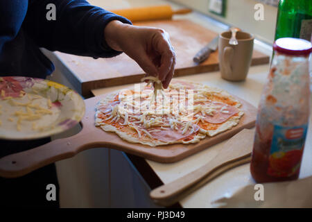 Adading shredded formaggio per pizza Foto Stock