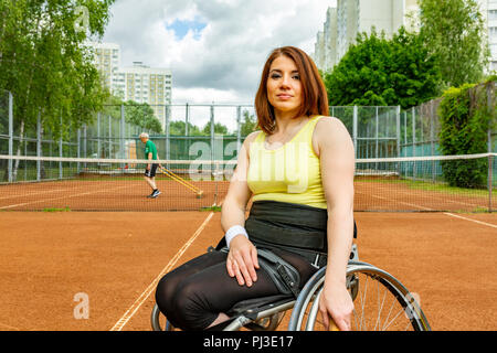 Disabilitato giovane donna sulla sedia a rotelle giocando a tennis sui campi da tennis. Foto Stock