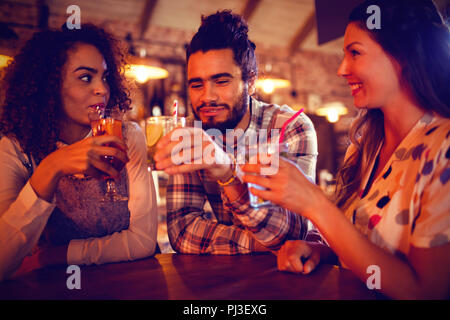 Giovani amici che interagiscono con ogni altro avente le bevande Foto Stock