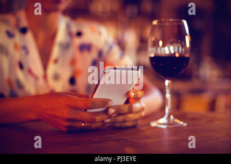 Sezione centrale della donna che utilizza il telefono cellulare Foto Stock