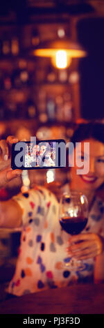 Giovani donne che prendono un selfie dal telefono cellulare mentre avente un vino rosso Foto Stock