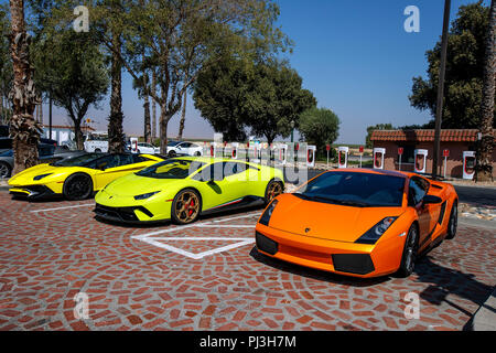 Tre Lamborghini auto sportive parcheggiata di fronte una Tesla Super stazione caricabatterie, Harris Ranch (3O8), Coalinga, California, Stati Uniti d'America Foto Stock