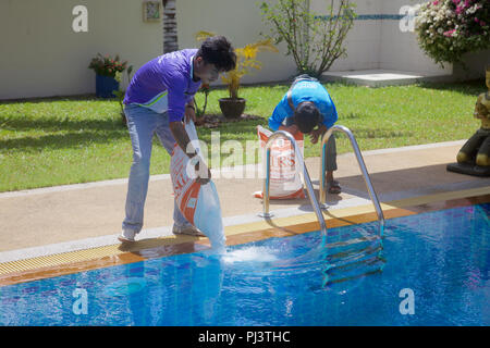 Sacchetti di sale che viene versato in una piscina di acqua salata in Thailandia Foto Stock