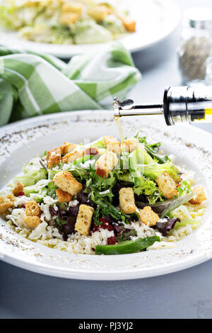 Casa con insalata di lattuga, formaggio e crostini con olio d'oliva versando sopra Foto Stock