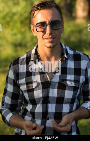 Ritratto di un uomo bello in occhiali da sole e controllato shirt Foto Stock