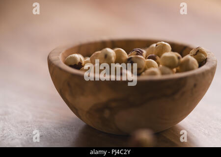 Sbucciate le nocciole in ciotola di legno Foto Stock