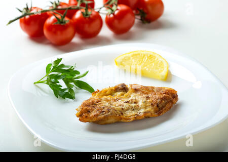 Un cervello di maiale schnizel sulla piastra con una fettina di limone e prezzemolo Foto Stock