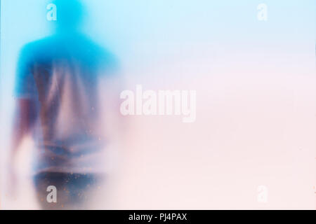 Silhouette di un irriconoscibile triste depresso uomo maschile con la testa verso il basso dietro il vetro sporco finestra Foto Stock