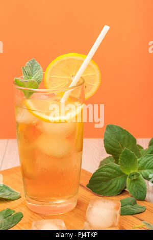 Il freddo estivo rinfrescante limonata con ghiaccio e le fette di limone e decorate con foglie di menta in un bicchiere alto sul bordo di taglio Foto Stock