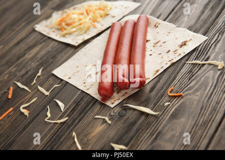 Salsicce affumicate, cavolo e pane pita isolate su backg in legno Foto Stock