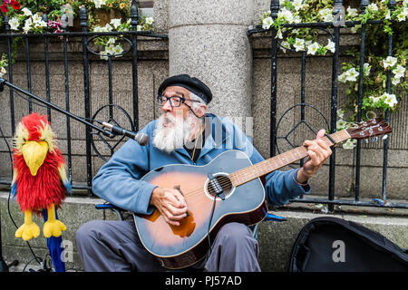 Un suonatore ambulante maturo a suonare la chitarra e cantare in una strada di Truro Cornwall. Foto Stock