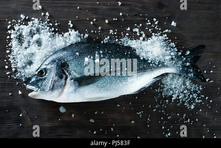 Pesce fresco dorado Orate di mare sulla lavagna nera con sale per riviste di cucina e ricette Foto Stock