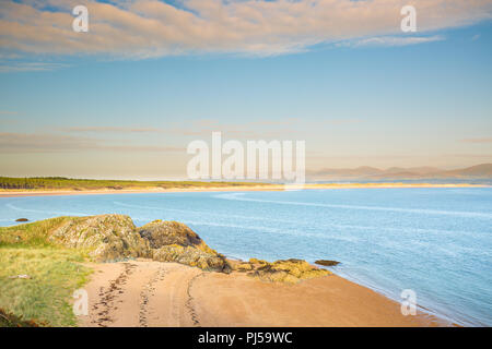 Estate stagcape da Ynys Llanddwyn (isola di marea in Anglesey, Galles) guardando verso la spiaggia sabbiosa di Newborough Beach e la catena montuosa di Snowdonia. Foto Stock