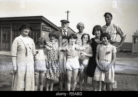 1930s, storico, immagine mostra una line-up di felice ragazze giovani lontano il giorno di una escursione con due maschi adulti e una signora anziana con loro, Inghilterra, Regno Unito. Foto Stock