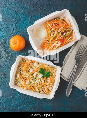 Cibo sano e consegna. Pilov da bulgur con carne di pollo, insalata di cavolo con carote, pomodori e cetrioli. Prendere via del rapporto giornaliero dei pasti nella scatola di carta Foto Stock