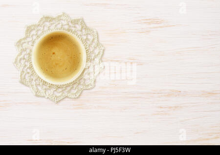 Tazza di caffè e un crochet centrino sul dipinto di bianco sullo sfondo di legno Foto Stock