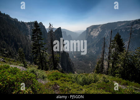 Una vista guardando verso il Parco Nazionale di Yosemite Valley con El Capitan sulla destra nel Parco Nazionale di Yosemite. Il fumo proveniente da incendi indugia nella valle. Foto Stock