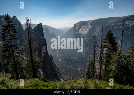 Una vista guardando verso il Parco Nazionale di Yosemite Valley con El Capitan sulla destra nel Parco Nazionale di Yosemite. Il fumo proveniente da incendi indugia nella valle. Foto Stock