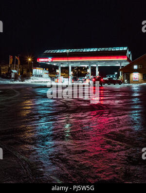 Circle K stazione di gas durante la notte con riflessi nella strada ghiacciata Foto Stock