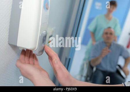 Distributore sapone con una mano che spinge su di esso Foto Stock