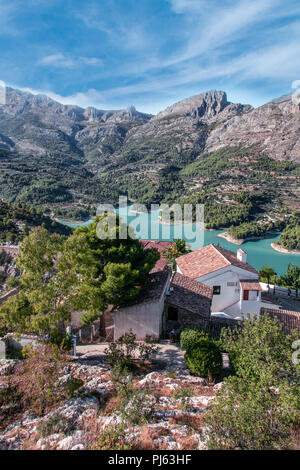 Case e acque turchesi serbatoio nella città di Guadalest a Valencia in Spagna, Europa. Belle montagne sullo sfondo. Foto Stock