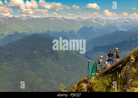 Giovane donna attraversando la voragine sul ponte di corde, Sochi, Russia Foto Stock