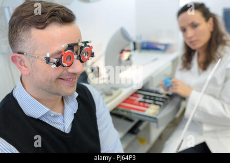 All'ottico optometrista femmina esame paziente sorridente Foto Stock