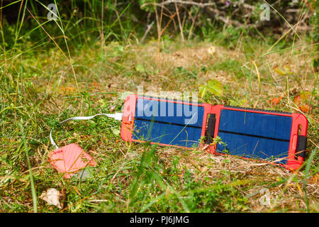 Portatile pannello solare carica la batteria di un powerbank - una fonte di energia alternativa nel concetto di selvatico Foto Stock