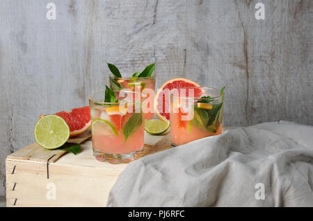 Cocktail di spremuta di succo di pompelmo rosso e foglie di limone delicate basilico, fettine di lime e refrigerate di cubetti di ghiaccio. Foto Stock