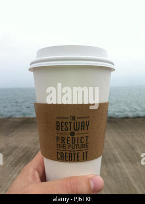 Prospettiva in prima persona di ispirazione qoute sulla tazza di caffè che si affaccia sulle acque nebbioso giorno Foto Stock