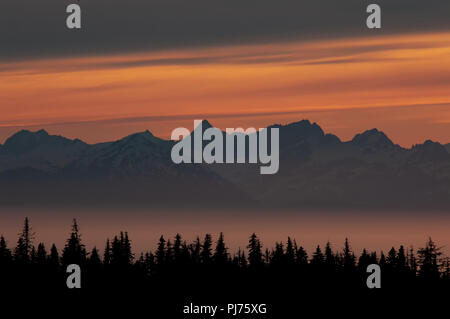 Mezzanotte bagliore del tramonto su picchi di montagna nella nebbia Kachemak Bay e Cook Inlet, Alaska. Foto Stock