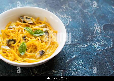 Close up spiralizzato zucca pasta fatta con il latte di cocco,salsa al curry e musrooms, blu sul tavolo di pietra, il fuoco selettivo, copia spazio per te Foto Stock