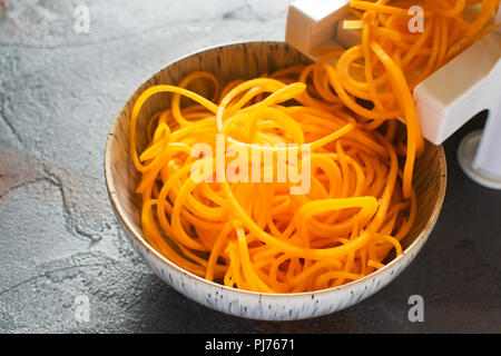 Close up di spirale la zucca, con spirazlizer sulla pietra grigia tabella, il fuoco selettivo, copia spazio per il testo Foto Stock