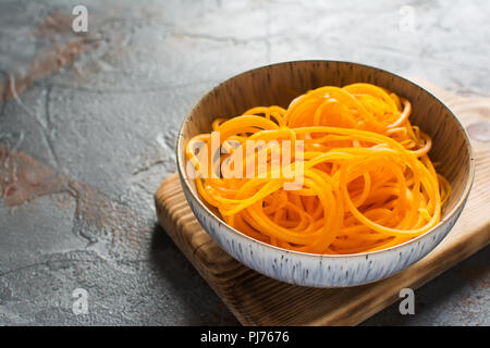 Close up spiralizzato zucca, sul boardm in legno grigio sul tavolo di pietra, il fuoco selettivo, copia spazio per il testo Foto Stock