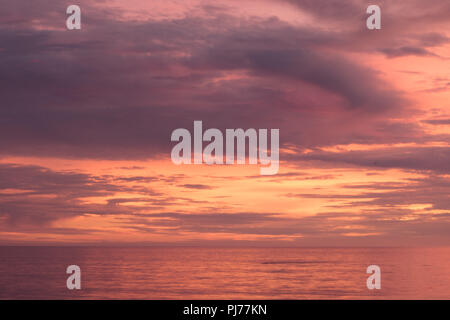 Tramonto spettacolare paesaggio marino, arancio, blu, giallo, magenta, sky gold si riflette nel mare oceano pacifico, foto di sfondo del sole tramontare sull orizzonte ami Foto Stock