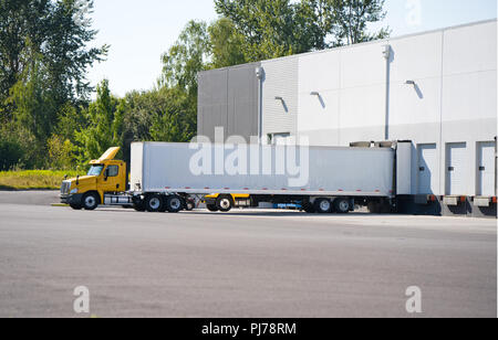 Un numero enorme di big rig semi camion vengono caricate e scaricate nei bacini dei grandi magazzini, si stacca semirimorchi, fissaggio già caricato, Foto Stock