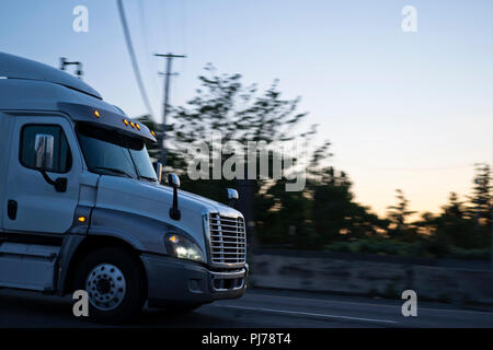 Big Rig semi carrelli trasportano merci sulle strade senza interruzione, a qualsiasi ora del giorno dalla mattina presto fino a tarda notte, i camionisti sono Foto Stock