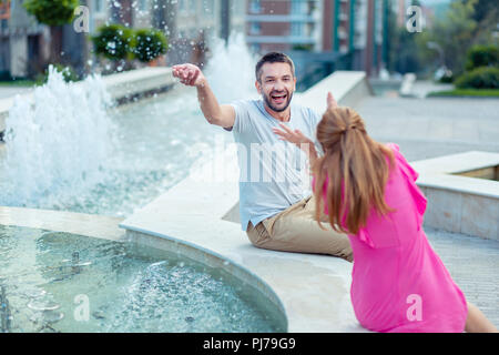 Felice gioiosa giovane divertendosi con vicino alla fontana Foto Stock