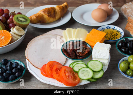 Sana colazione selezione: olive, pomodori, cetrioli, prosciutto, formaggio, pane, croissant, uova, il fuoco selettivo Foto Stock