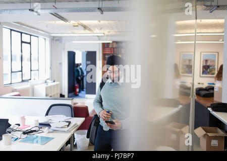 Commerciante indiano in turbante utilizzando smart phone in office Foto Stock