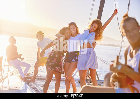 Giocosi amici delle donne che danzano sul catamarano soleggiato Foto Stock
