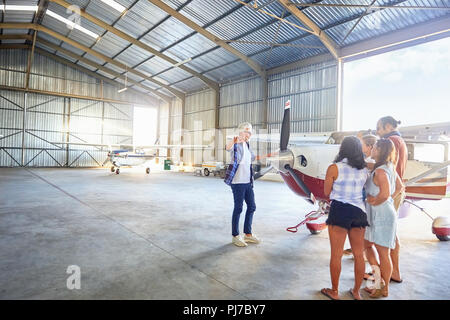 Progetto pilota a parlare con gli amici in prop aereo in hangar aereo Foto Stock