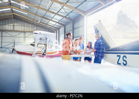 Gli amici di parlare, pianificazione viaggio in hangar aereo Foto Stock