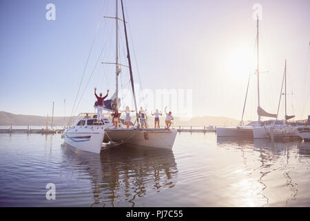 Ritratto amici sventolare sul catamarano nel porto di sole Foto Stock