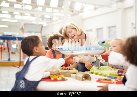 Insegnante che mostra aeroplano giocattolo per bambini nel centro di scienze naturali Foto Stock