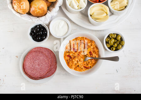 Tradizionale colazione Turca, vista dall'alto: uova cotte menemen, pogaca pasties, verdure, formaggi, olive e halal turchia salame, il fuoco selettivo Foto Stock