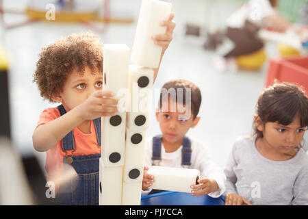 Bambini curiosi di impilamento dei dominos di grandi dimensioni in mostra interattiva in science center Foto Stock